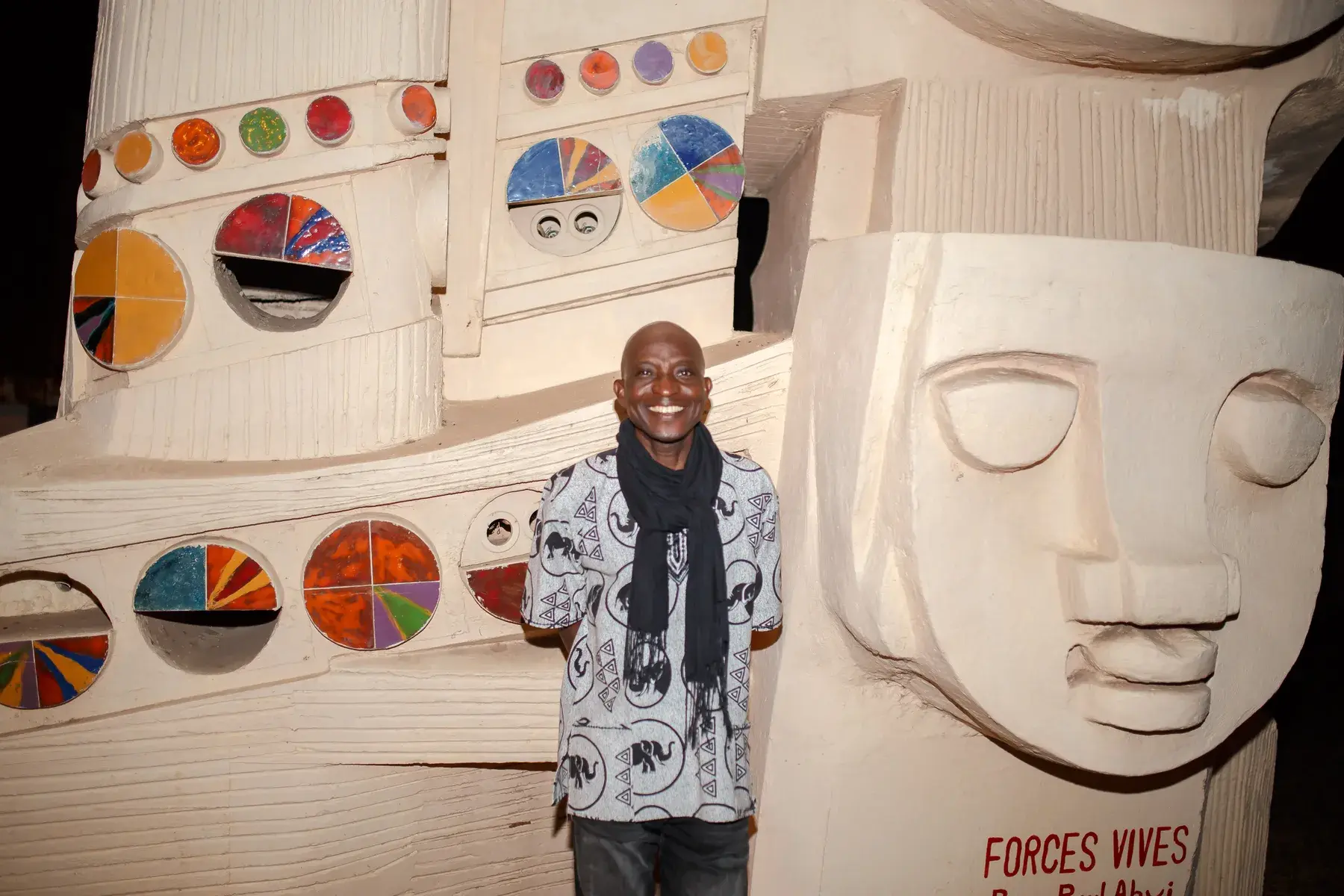 Richard Meseko in front of a sculpted mural.
