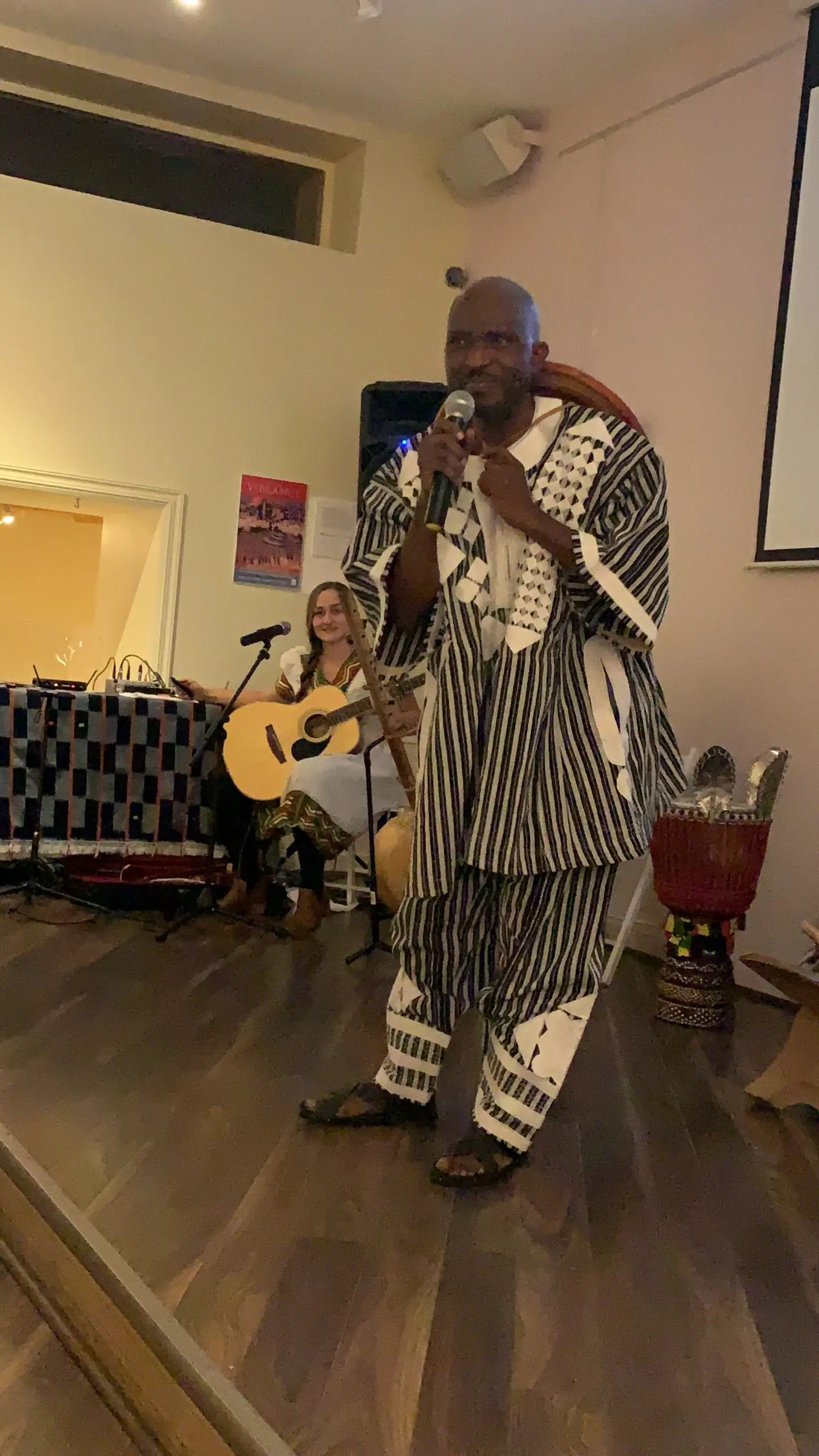 Richard Meseko performing on a small stage with a microphone.