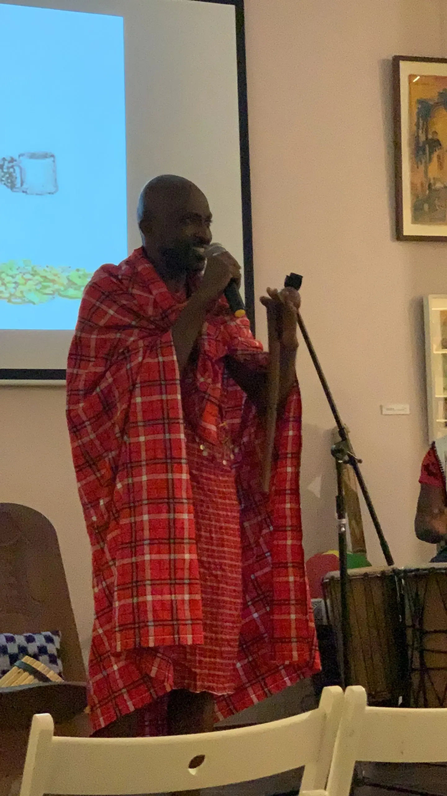 Richard Meseko in a red robe, singing into a microphone.