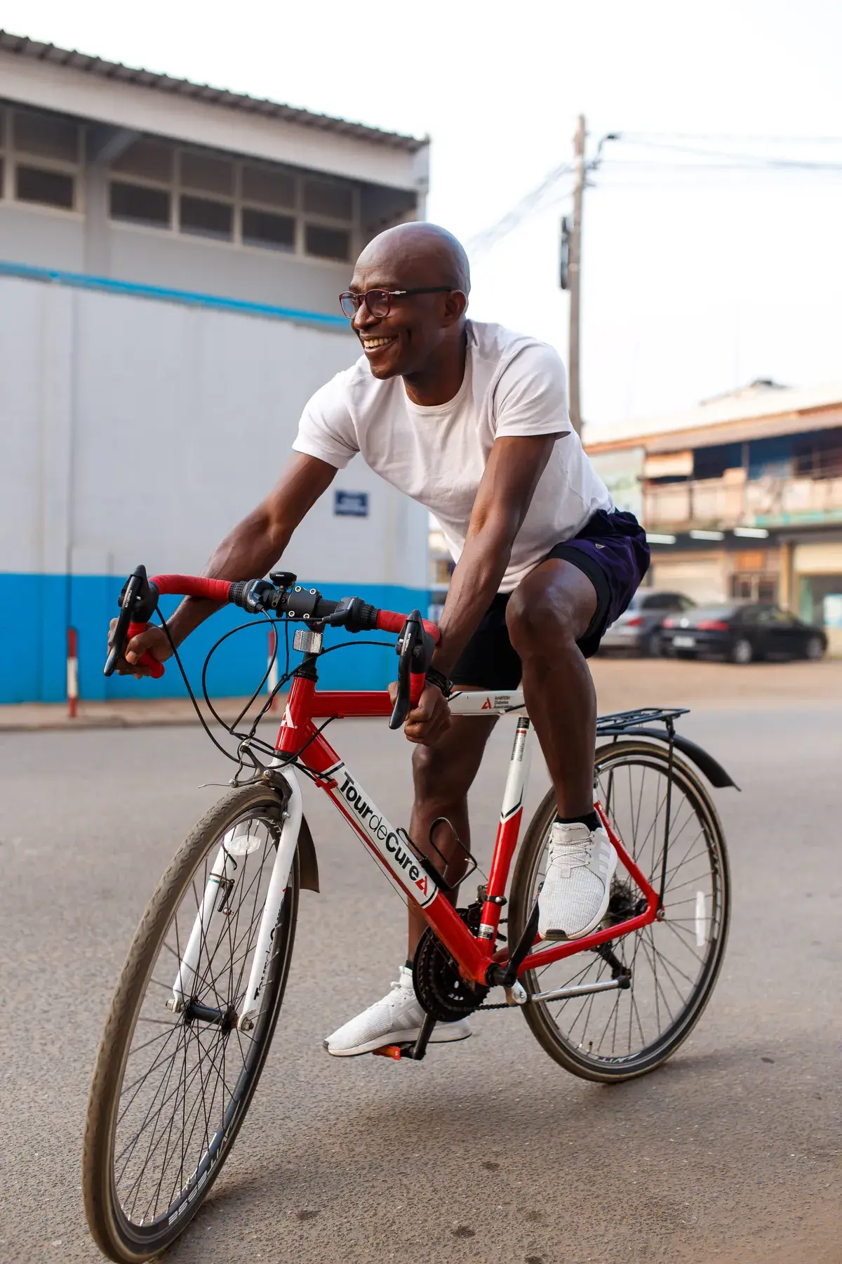 Richard Meseko cycling past a stadium wall.