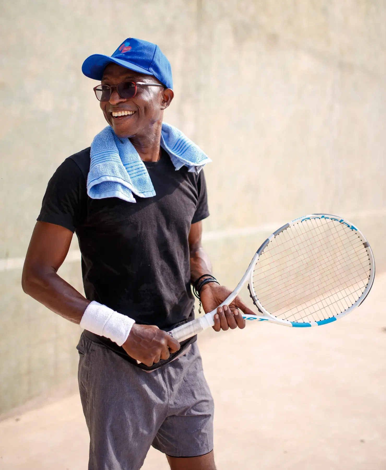 Richard Meseko with a racket and a towel around his neck.