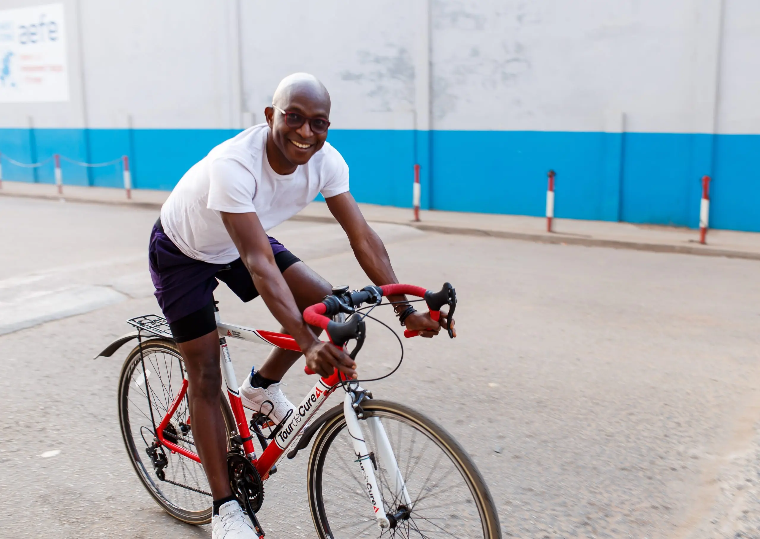 Richard Meseko cycling on a red road bike.