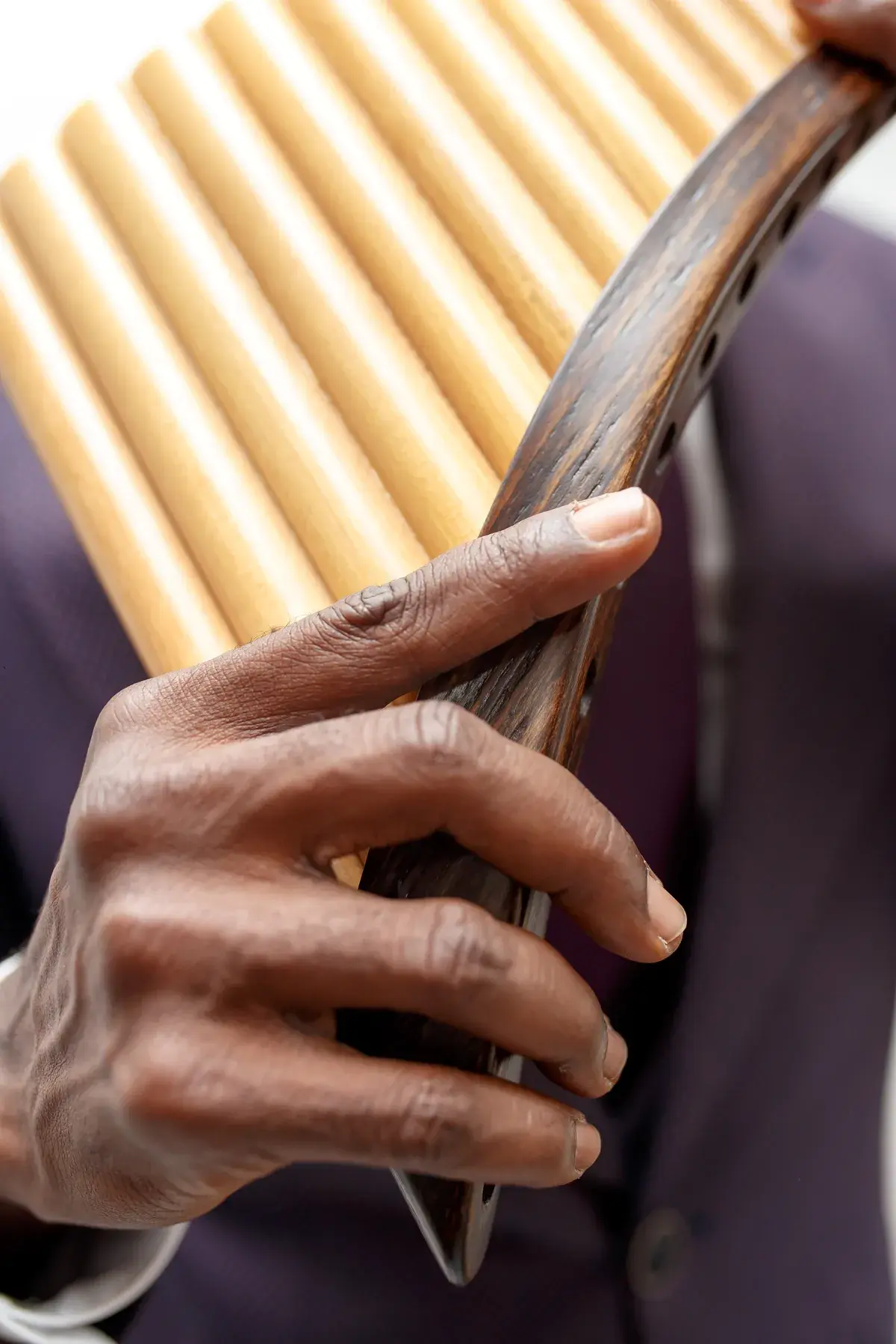 Close-up of a hand on the bamboo reeds of the pan flute.