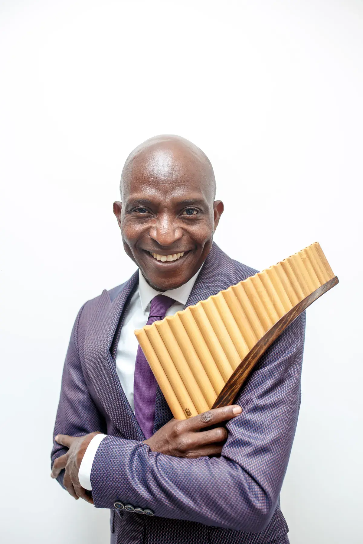 Richard Meseko smiling, holding the pan flute to his chest.